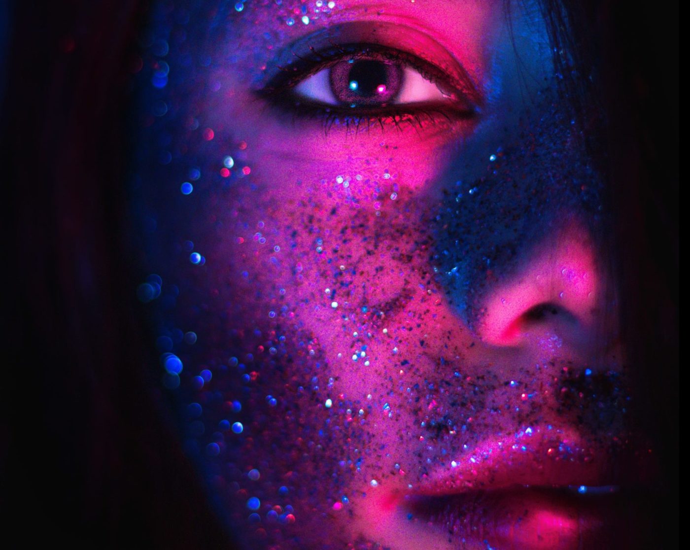 Rostro femenino iluminado con maquillaje neón y glitter, representando el concepto de brillo en fiestas de Shining Bar